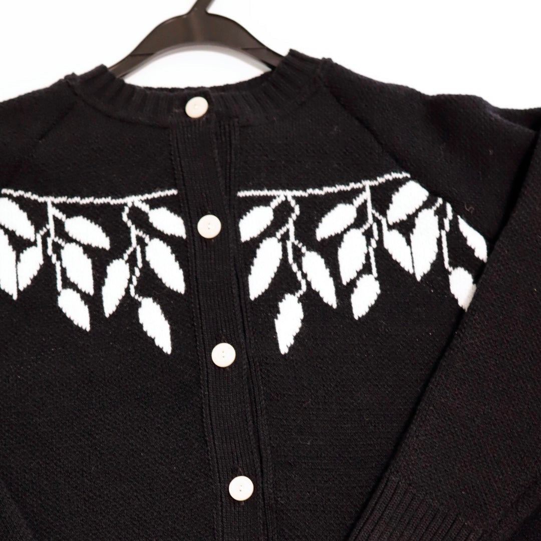 Black cardigan with white button details and leaf pattern on a white background